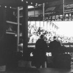 Formula 1 crowd watches screen with qatar airways advertisement.