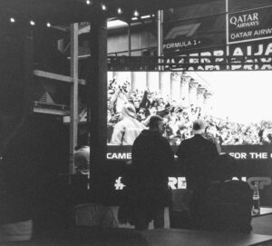 Formula 1 crowd watches screen with qatar airways advertisement.
