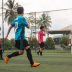 2 boys playing soccer during daytime