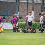 Soccer player injured on the field with teammates and referee assistance in Texcoco, Mexico.