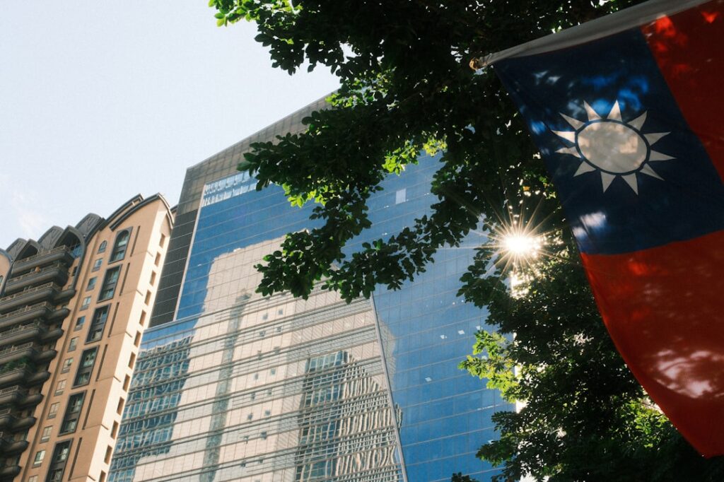 Taiwanese flag hangs near modern buildings under sunlight
