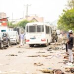A street cluttered with debris, cars, people, and a truck, reflecting urban chaos.