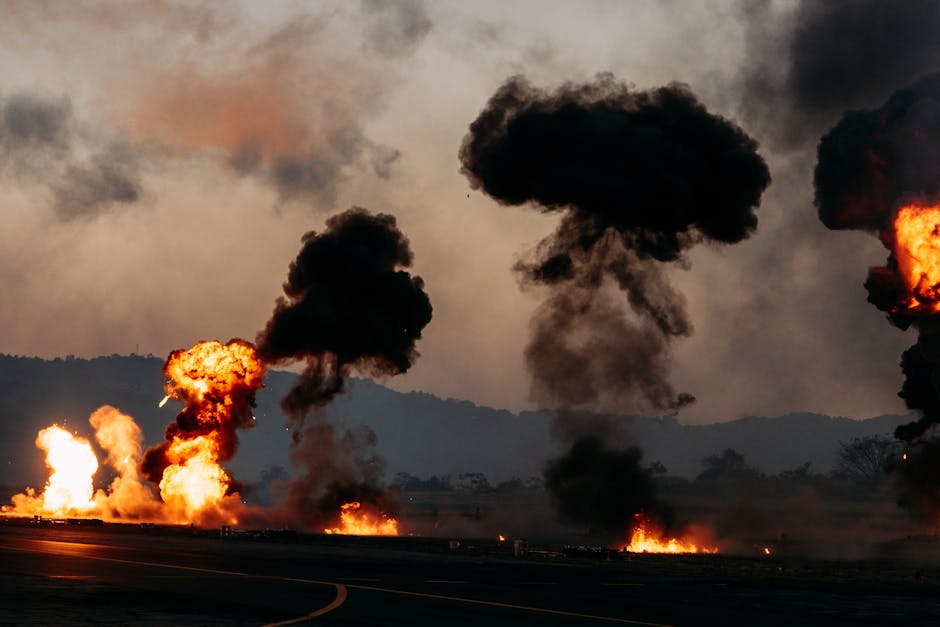 Dramatic scene with explosions and thick black smoke rising in an outdoor setting.