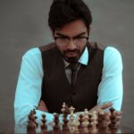 Crop concentrated serious male in classy suit thinking about next move while playing chess in studio