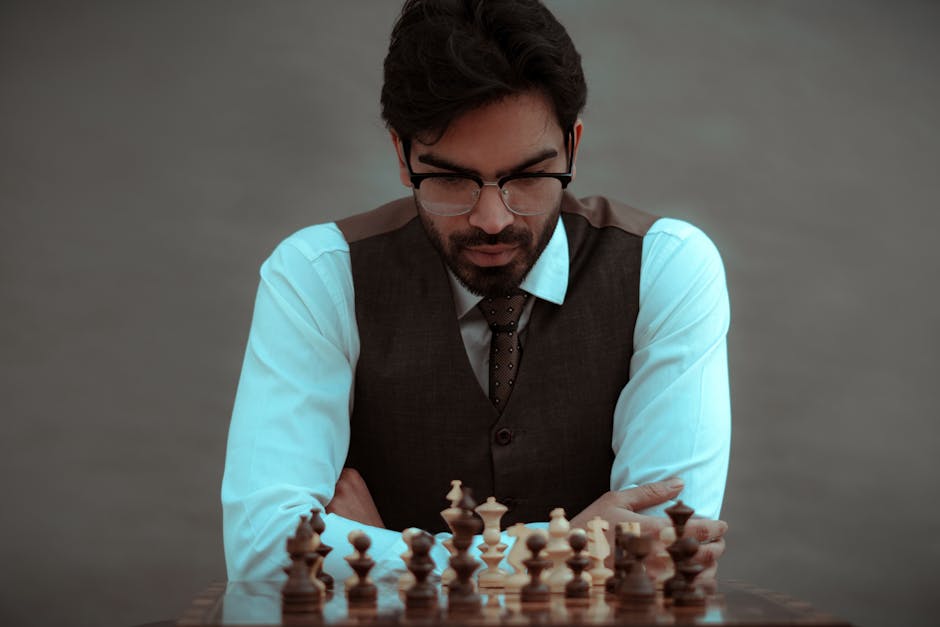 Crop concentrated serious male in classy suit thinking about next move while playing chess in studio