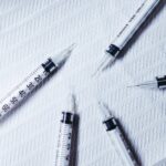Multiple syringes arranged on a textured white surface, showcasing healthcare tools.
