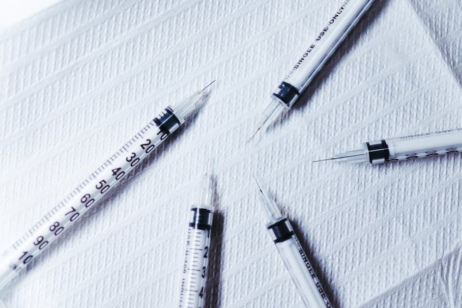 Multiple syringes arranged on a textured white surface, showcasing healthcare tools.