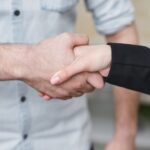 Close-up of two individuals shaking hands symbolizing business agreement and partnership.