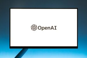 Minimalistic display of OpenAI logo on a monitor with a gradient blue background, representing modern technology.