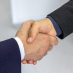 Close-up of two businessmen shaking hands, symbolizing agreement and partnership.
